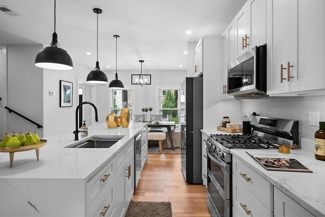 kitchen featuring stainless steel appliances, light hardwood / wood-style floors, tasteful backsplash, sink, and light stone countertops