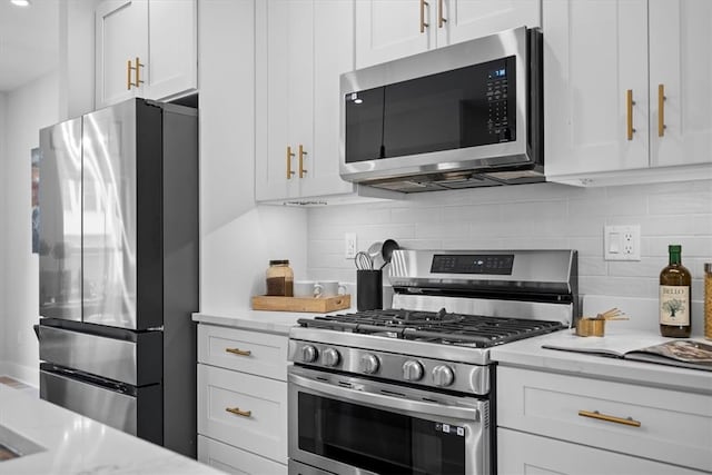 kitchen featuring white cabinets, backsplash, appliances with stainless steel finishes, and light stone countertops