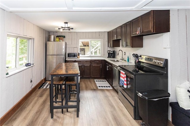 kitchen featuring a wealth of natural light, a sink, light wood-style floors, and appliances with stainless steel finishes