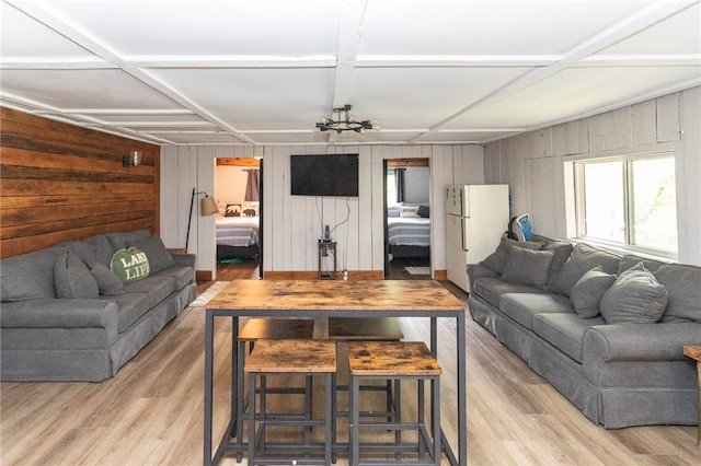 living room featuring light wood-type flooring, wood walls, and coffered ceiling