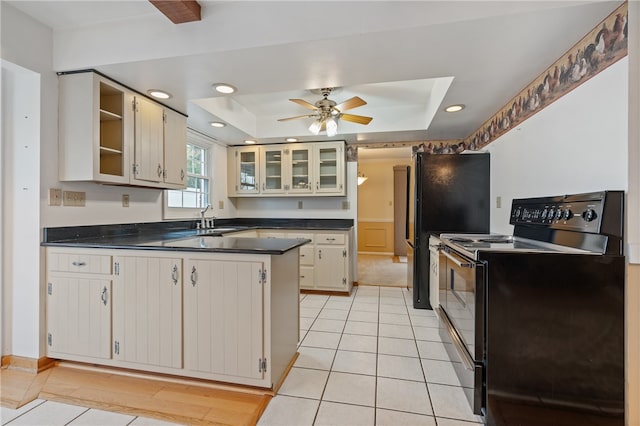 kitchen with ceiling fan, black electric range oven, a tray ceiling, and light tile patterned floors