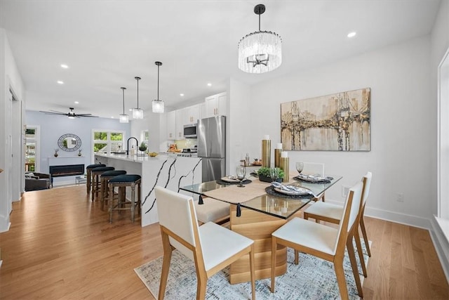 dining room with light hardwood / wood-style floors and ceiling fan with notable chandelier