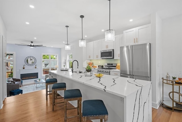 kitchen featuring backsplash, an island with sink, white cabinets, appliances with stainless steel finishes, and light hardwood / wood-style floors