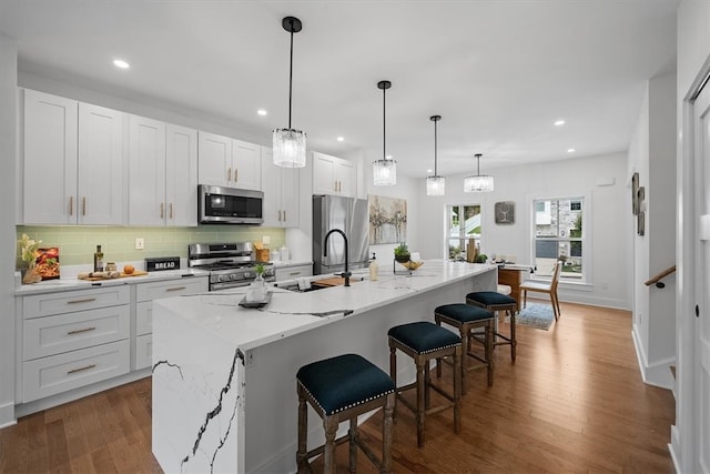 kitchen featuring stainless steel appliances, a kitchen island with sink, and wood-type flooring