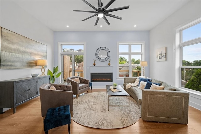 living room featuring ceiling fan, a wealth of natural light, and light hardwood / wood-style flooring