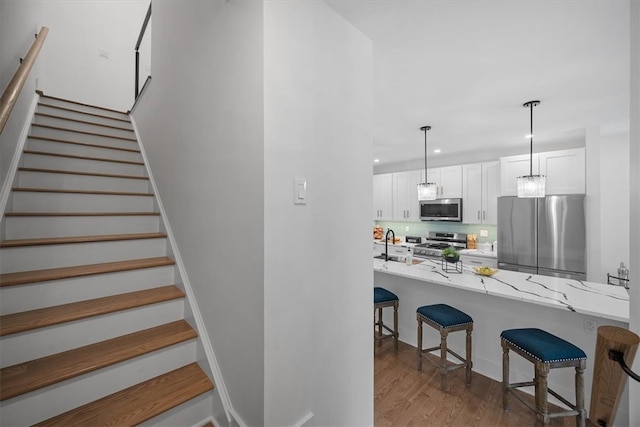 stairs featuring hardwood / wood-style flooring and sink