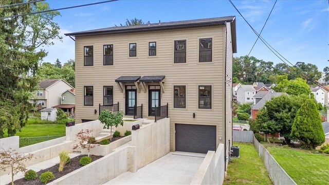 view of front of house with cooling unit, a garage, and a front lawn