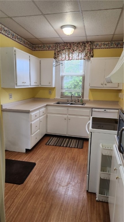 kitchen with dark wood-type flooring, a drop ceiling, white cabinets, white range with electric cooktop, and sink