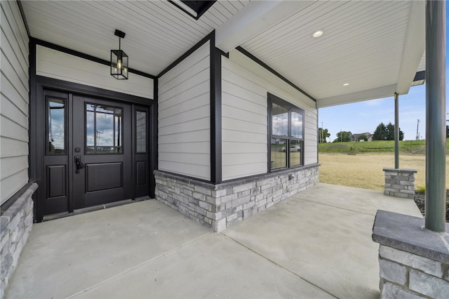 doorway to property featuring a lawn and covered porch