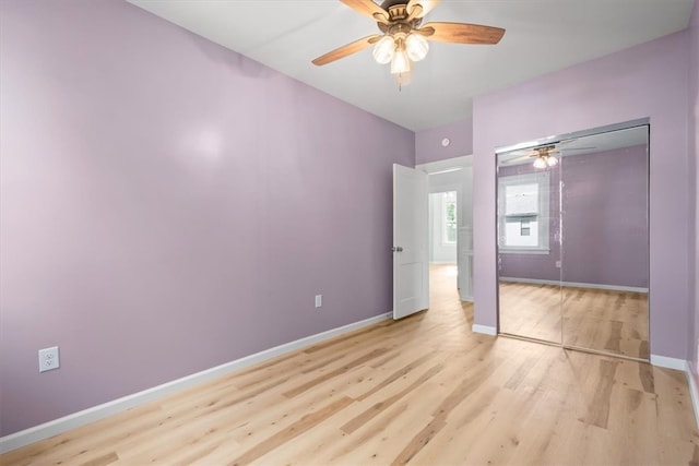 unfurnished bedroom with light wood-type flooring, ceiling fan, and a closet