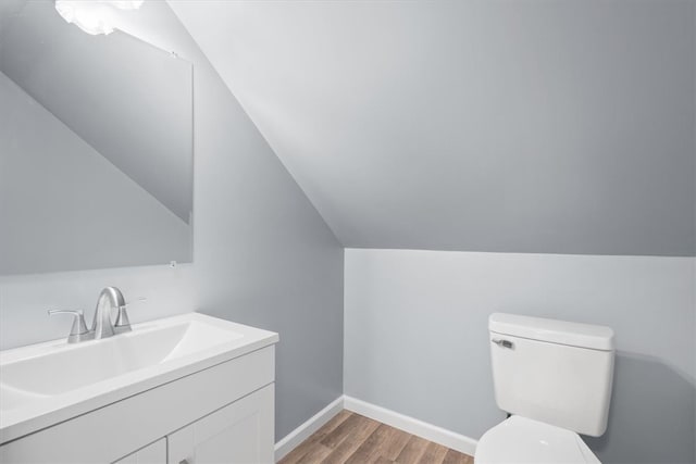 bathroom with hardwood / wood-style flooring, toilet, vanity, and lofted ceiling