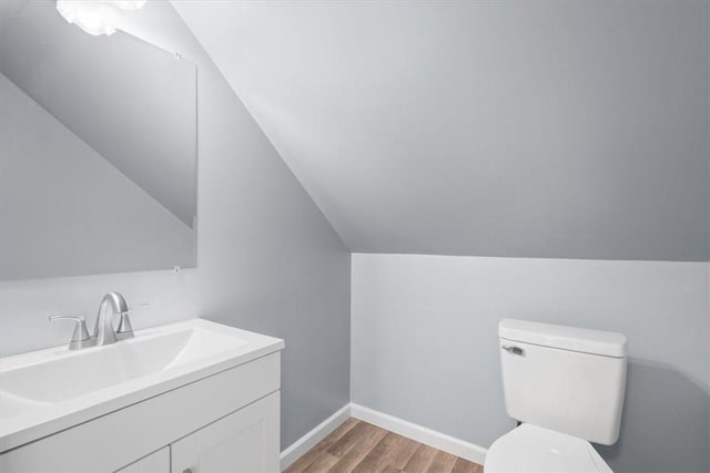 bathroom with vanity, vaulted ceiling, toilet, and hardwood / wood-style floors