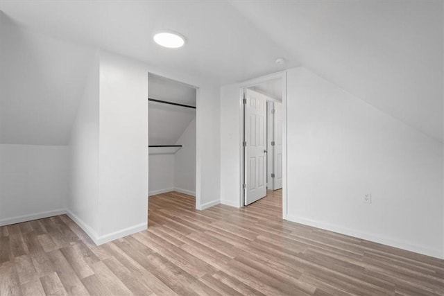 additional living space with light hardwood / wood-style floors and vaulted ceiling