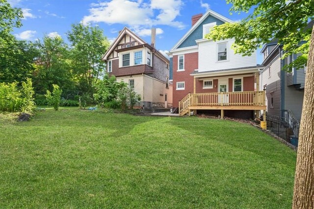 back of property featuring a lawn and a deck