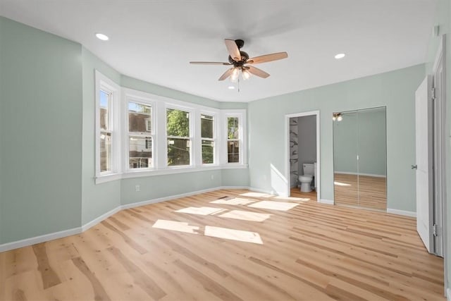 unfurnished bedroom with light wood-type flooring, connected bathroom, and ceiling fan