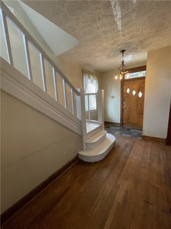 entrance foyer with a textured ceiling, dark hardwood / wood-style floors, and a notable chandelier