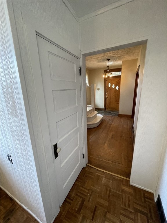 hall with dark parquet floors and an inviting chandelier