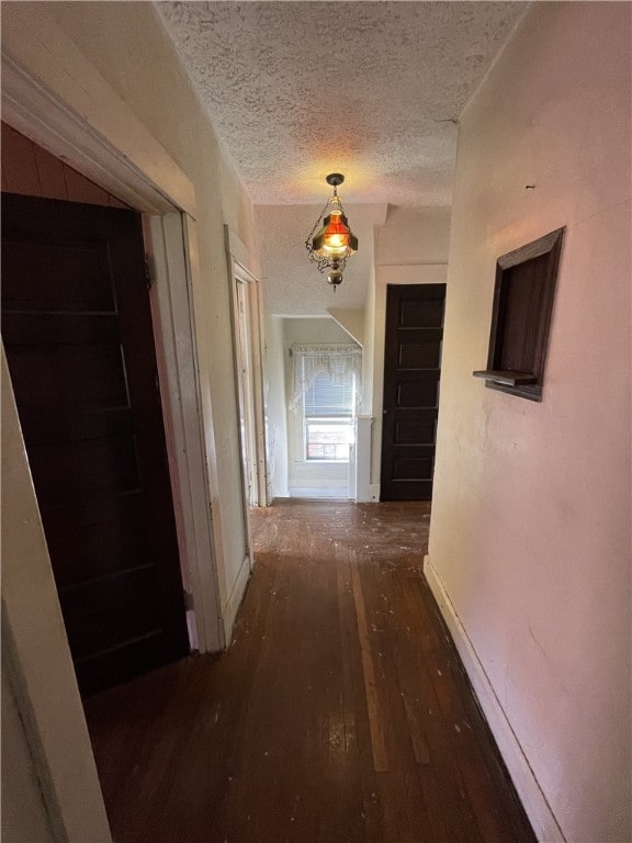 hallway featuring a textured ceiling and dark hardwood / wood-style flooring