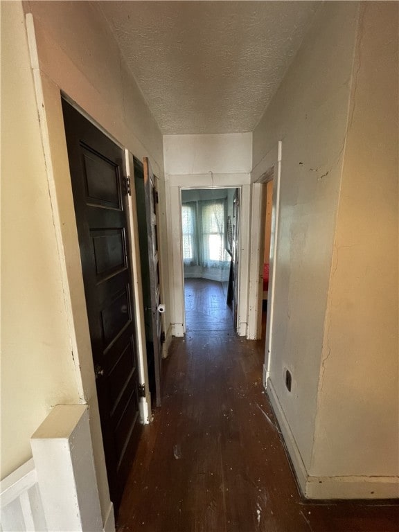 corridor featuring a textured ceiling and dark hardwood / wood-style flooring