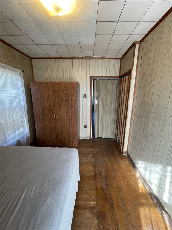 unfurnished bedroom featuring wood walls, dark hardwood / wood-style floors, and ornamental molding