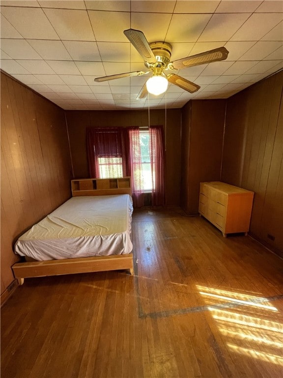 unfurnished bedroom featuring hardwood / wood-style floors, ceiling fan, and wooden walls