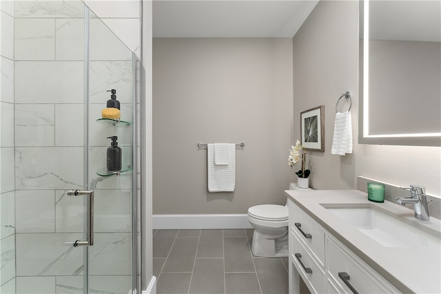 bathroom with a shower with shower door, toilet, vanity, and tile patterned floors