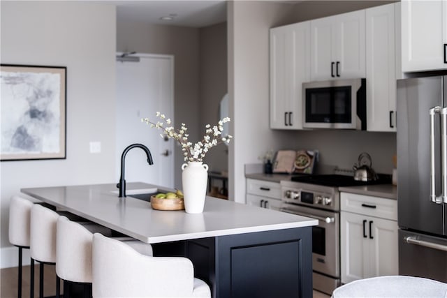 kitchen featuring a center island with sink, white cabinetry, and high quality appliances