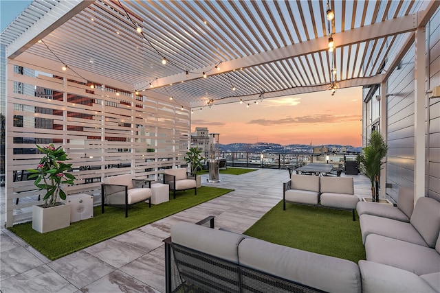 patio terrace at dusk featuring a pergola, an outdoor hangout area, and a balcony