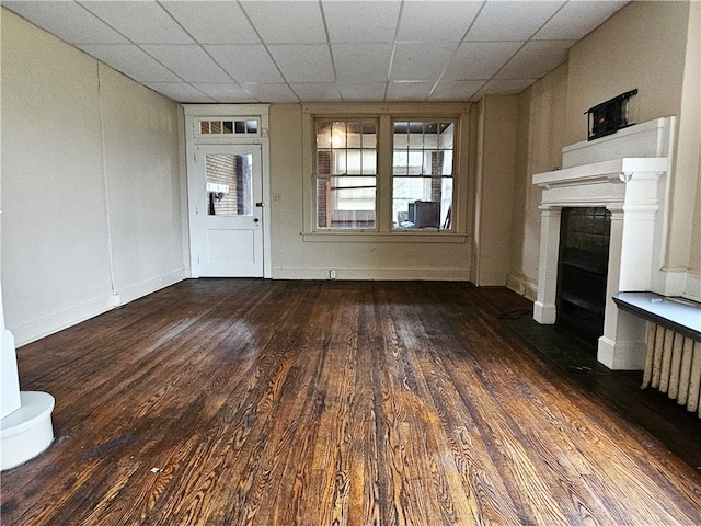 unfurnished living room with dark hardwood / wood-style floors and a paneled ceiling