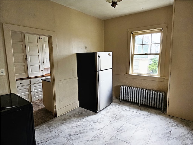 kitchen featuring radiator, white cabinets, and stainless steel refrigerator