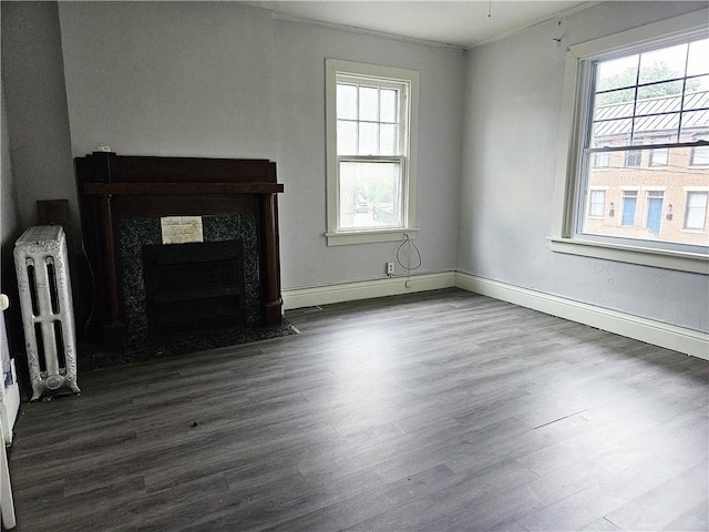 unfurnished living room with dark hardwood / wood-style flooring, crown molding, radiator, baseboard heating, and a high end fireplace