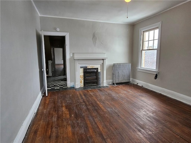 unfurnished living room with crown molding, wood-type flooring, a stone fireplace, and radiator heating unit