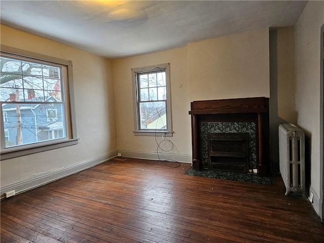 unfurnished living room with radiator heating unit, dark hardwood / wood-style flooring, and a premium fireplace