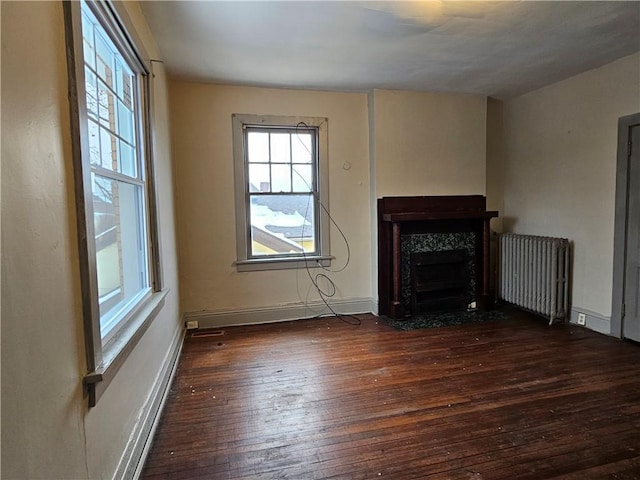 unfurnished living room with dark hardwood / wood-style floors, a baseboard radiator, and radiator heating unit