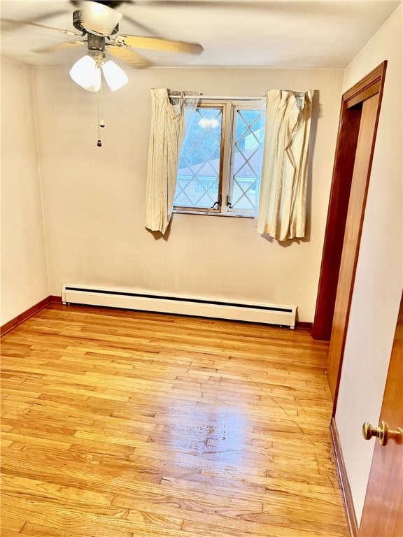 spare room featuring a baseboard radiator, light hardwood / wood-style flooring, and ceiling fan