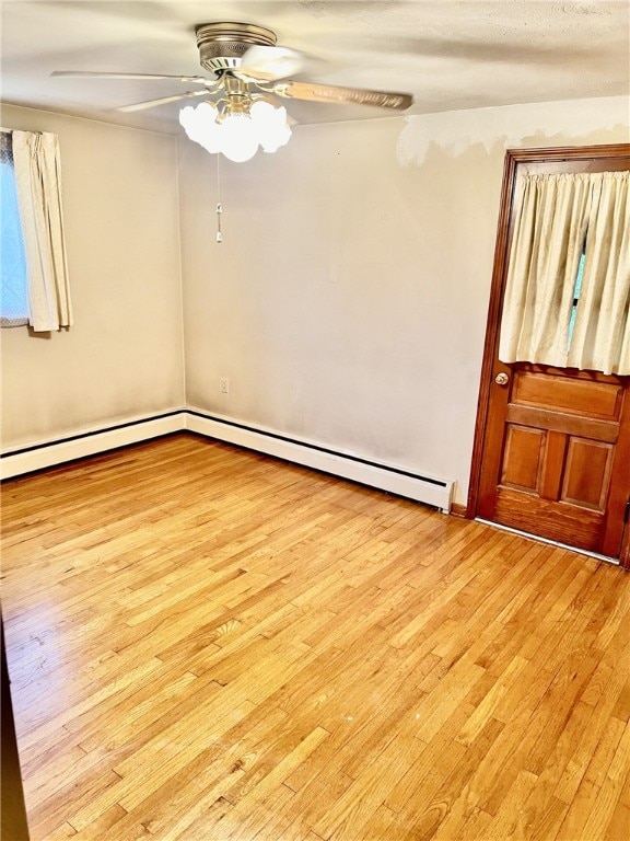 empty room with ceiling fan, light hardwood / wood-style flooring, and a baseboard heating unit