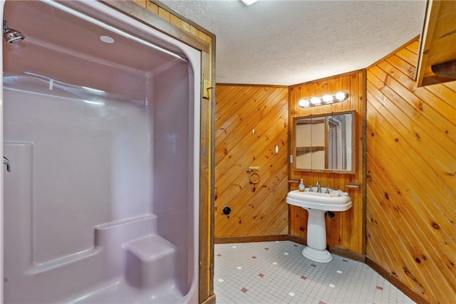 bathroom with tile patterned flooring, wooden walls, and a textured ceiling