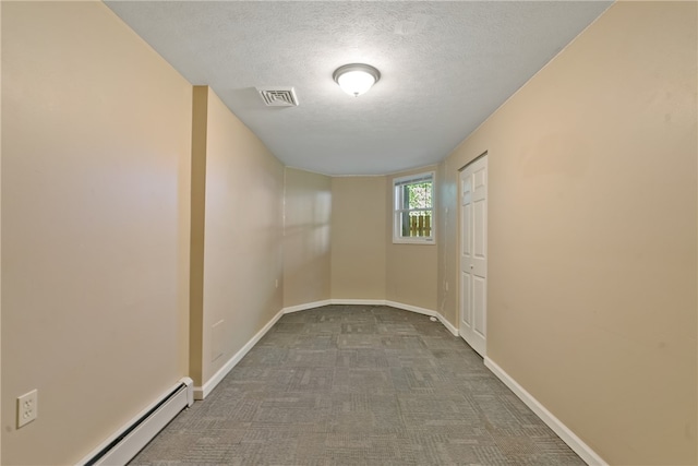 empty room featuring a textured ceiling, carpet, and baseboard heating