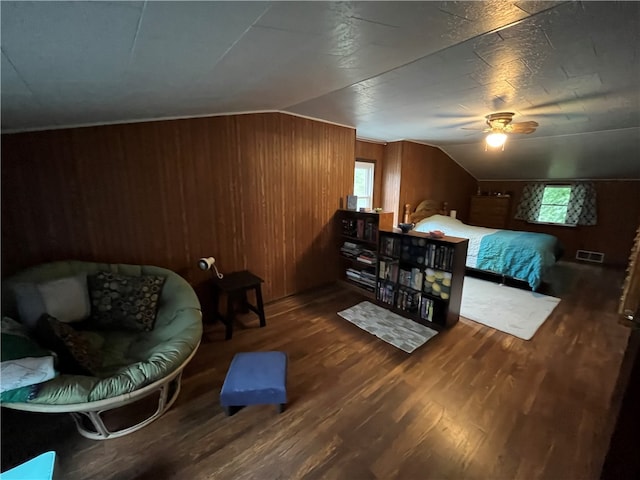 bedroom with ceiling fan, dark hardwood / wood-style flooring, wooden walls, and lofted ceiling