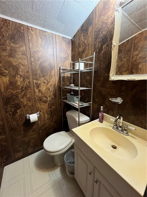 bathroom featuring wooden walls, toilet, vanity, and tile patterned floors