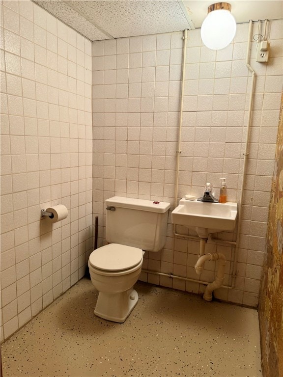 bathroom with sink, tile walls, and toilet