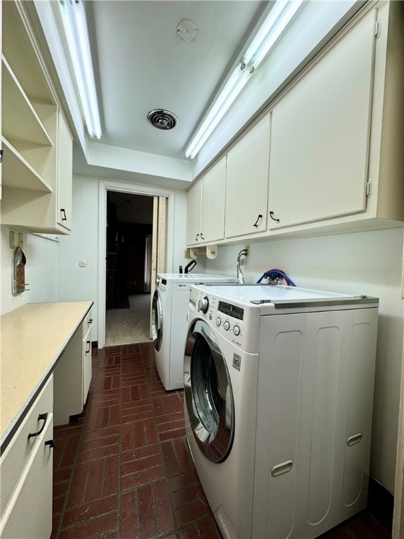 clothes washing area featuring separate washer and dryer and cabinets