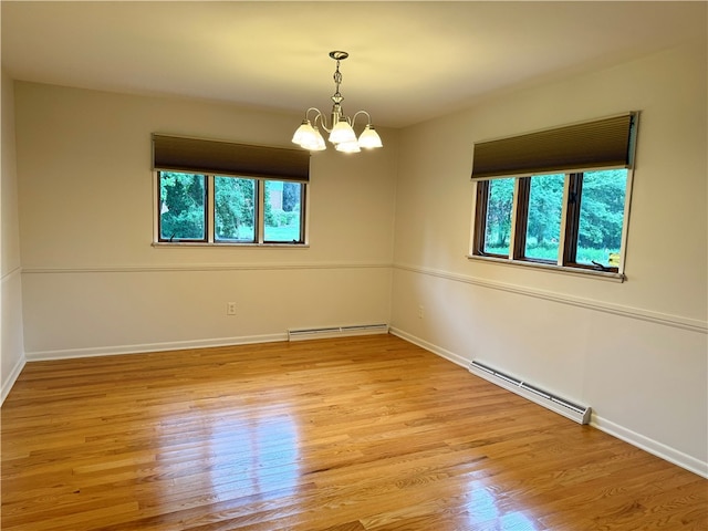 unfurnished room featuring light hardwood / wood-style flooring, a chandelier, and a baseboard heating unit