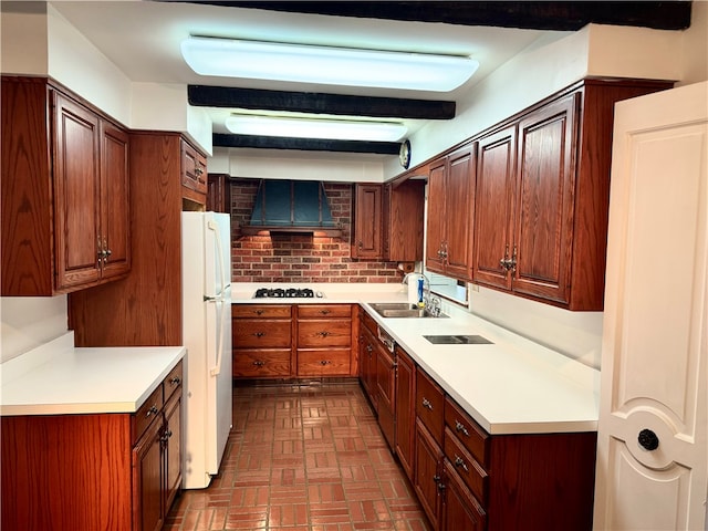 kitchen with tasteful backsplash, sink, stainless steel gas stovetop, wall chimney range hood, and white fridge