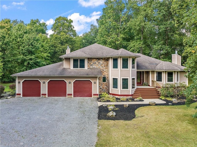 tri-level home featuring stone siding, driveway, a chimney, and a front lawn