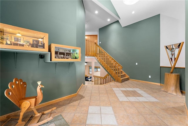 interior space with tile patterned flooring, recessed lighting, baseboards, and a towering ceiling