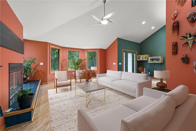 living area featuring high vaulted ceiling, a ceiling fan, wood finished floors, a glass covered fireplace, and recessed lighting