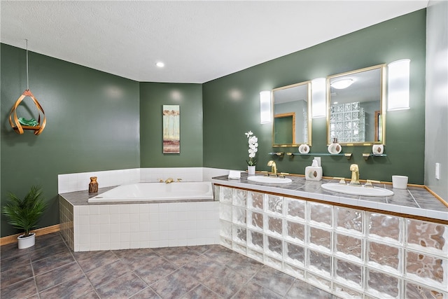 bathroom featuring dual vanity, a relaxing tiled tub, a textured ceiling, and tile patterned flooring