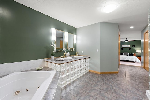 ensuite bathroom with tile patterned floors, a sink, connected bathroom, baseboards, and a whirlpool tub