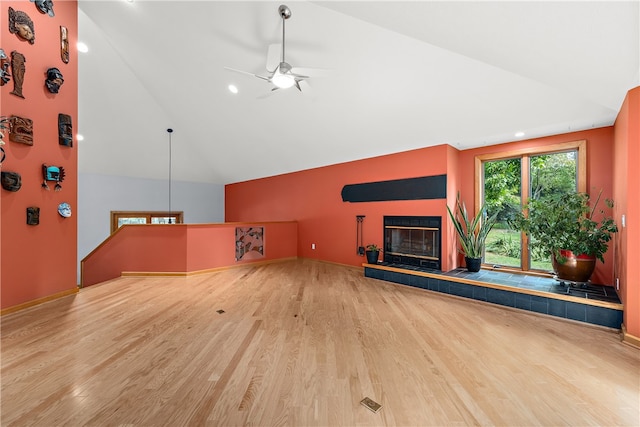 unfurnished living room with ceiling fan, light hardwood / wood-style floors, vaulted ceiling, and a tile fireplace